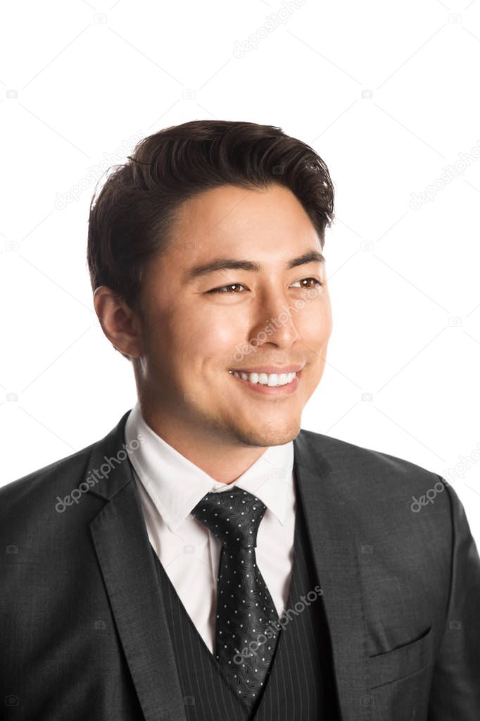 Handsome young entrepreneur with a smile standing against a white background wearing a grey suit, tie and vest. 
