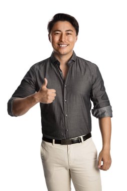 Gri gömlek ve kemerli bej pantolon giyen çekici adam, yüzünde başparmak yapıyor bir gülümseme ile beyaz bir arka plan karşı duran. 