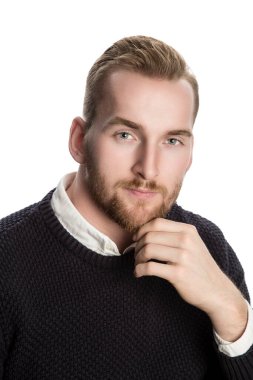 Çekici ve sakallı Avrupalı bir adam ablack örülmüş süveter, güzel gözler ve sarı saçlar giyiyor. Bir eli çenesine değmiş, beyaz arka plan..