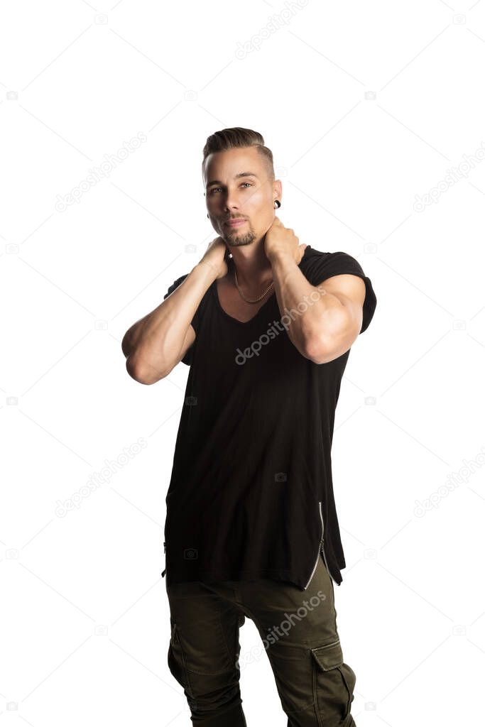 Tough, fit lookingand handsome Caucasian guy in plain black shirt standingcasually with both hands on his neck.