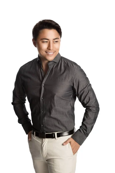 一个英俊的日本企业家在镜头前微笑 双手插在口袋里 头戴灰色领子的长袖和亮晶晶的裤子 图库图片