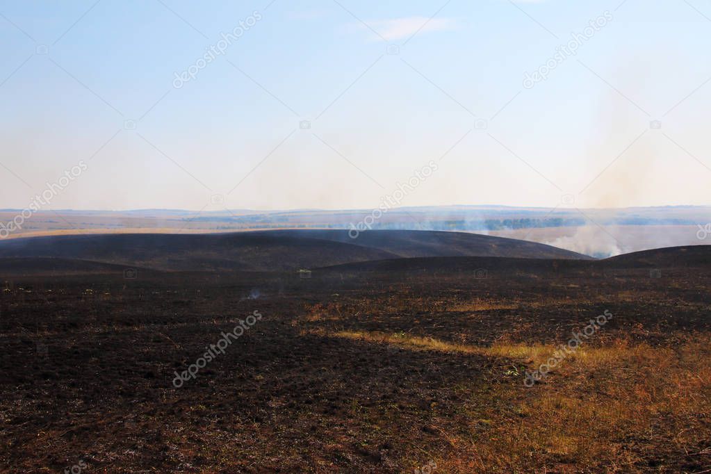 Burnt out smoking steppe after disastrous fire