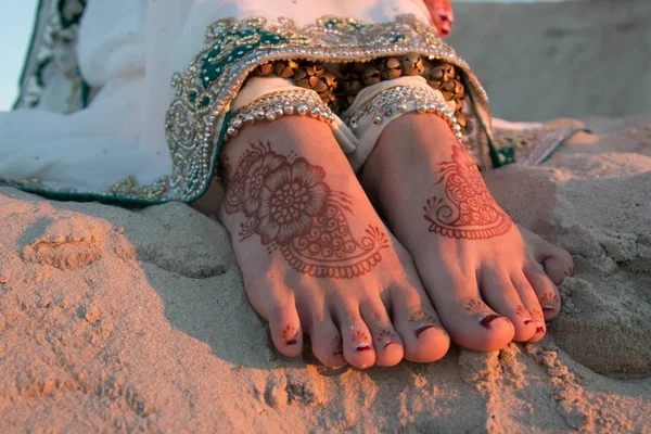 Indian woman\'s feet painted with henna. Legs with bracelets. Jewelry on its feet. Indian jewelry. Feet in the sand.