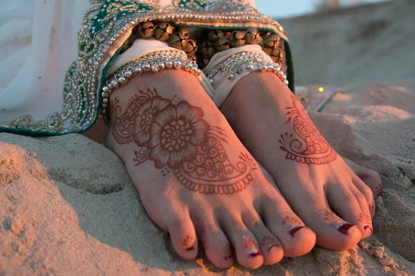 Indian woman's feet painted with henna. Legs with bracelets. Jewelry on its feet. Indian jewelry. Feet in the sand.