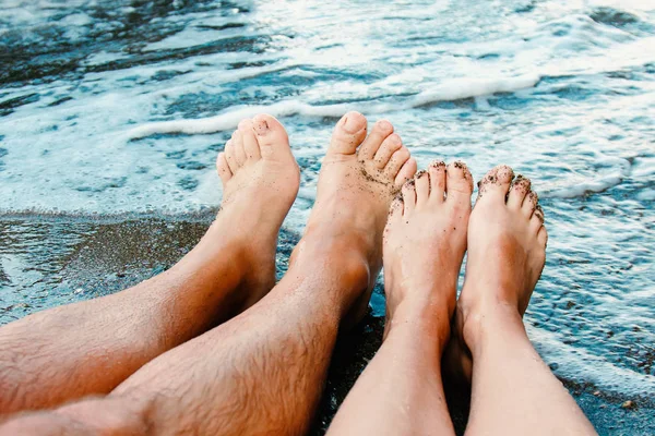 Male and female feet on the sandy beach by the sea. Feet by the sea. Feet on coast. Feet on the sand by the sea