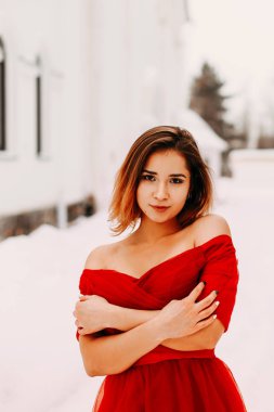 Sokakta kışın kırmızı elbiseli güzel bir kız portresi. Kar çevresinde