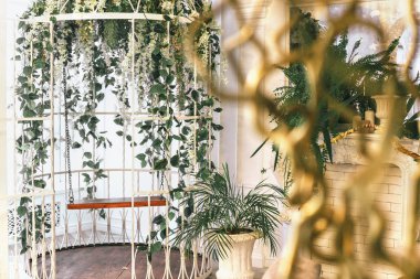 Büyük beyaz kafes çiçeklerle süslenmiş. Bir salıncak ve çiçekler ile kafes.