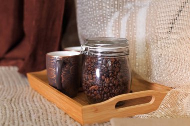 bir fincan kahve ve kahve çekirdekleri bir ahşap tepsi bir kavanoz