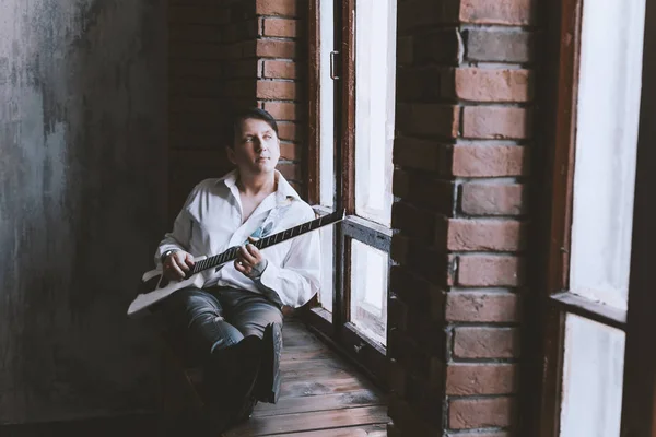 Homem Com Uma Guitarra Sentado Uma Grande Janela Uma Sala — Fotografia de Stock