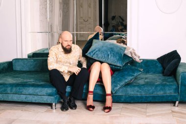 Kadın yastık ve şeyler ile kaplıdır. Kadın kanepenin üstünde bir yastık yığınının üstünde yatıyor. Kanepede oturan, tatmin edici bir yüzü olan bir adam. Sonraki bir kadın şeyler ile doludur