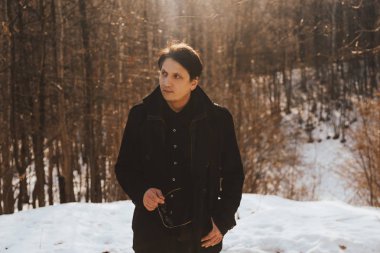 Ormanda yürüyen bir ceket ve güneş gözlüğü genç bir adamın portresi. Dağlar ve ormanlar arasında seyahat. Ormanda yürüyüş genç adam güneşli bahar günü.