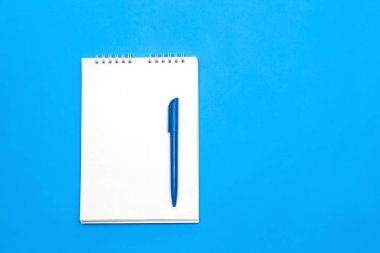 Arka plan için mavi ahşap masa üzerinde kalemi kağıdına boş Not üstten görünüm.