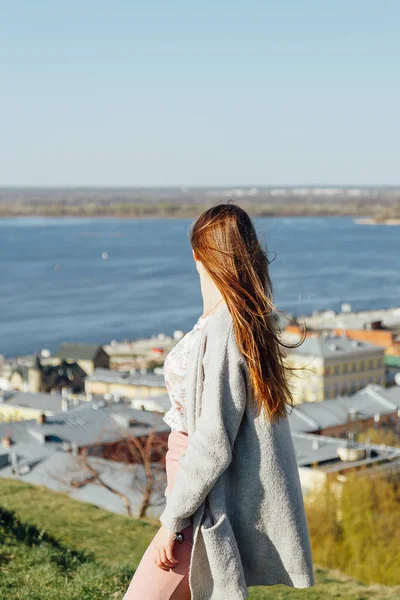 Jolie femme rêveuse assise près de la rivière de la ville . — Photo