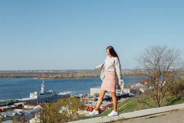 Genç bir kız şehir koyunda set üzerinde yürüyor.