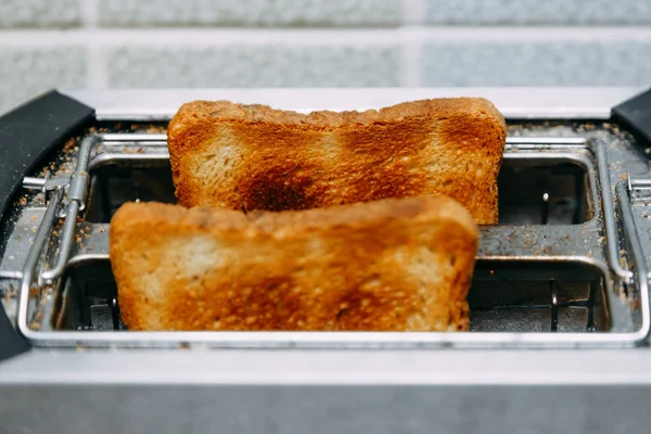 Rostat bröd i en brödrost. Brödrost med välsmakande frukost rostat bröd på bordet — Stockfoto