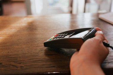 Terminalin ve müşterinin kredi kartının olduğu el. Kartla ödeme