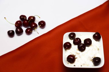 Kırmızı ve beyaz arka planda bir şişe süzme peynir ve kiraz çilek süt