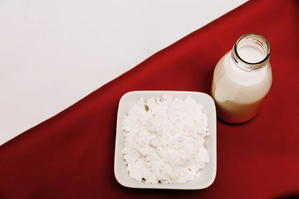 Mjölk i en flaska keso och körsbärs bär på en röd och vit bakgrund — Stockfoto
