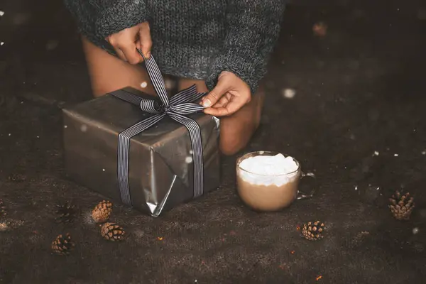 Envoltura de regalo de Navidad. Las manos de la mujer empacando una caja de regalo de Navidad sobre fondo oscuro — Foto de Stock