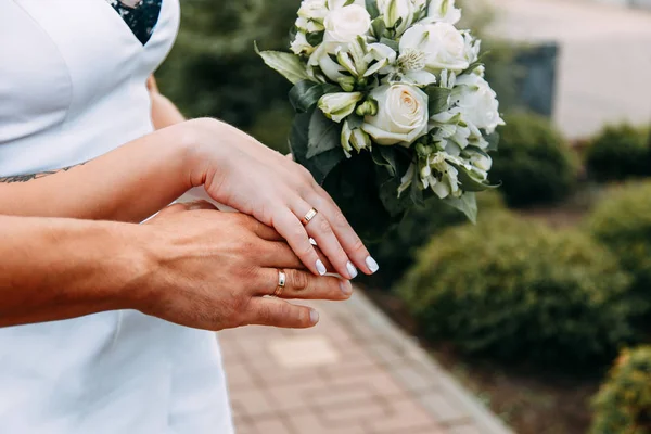 Mani della sposa e dello sposo sul bouquet — Foto Stock