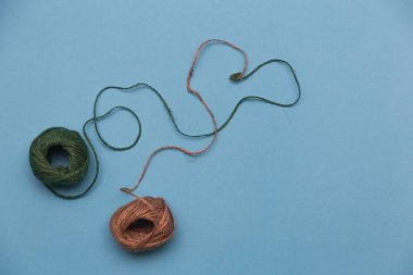 Beyaz arka planda yün bir top ve kalp şeklinde yakın plan. Kalp şeklinde yün iplik. Aşk Tığ işi