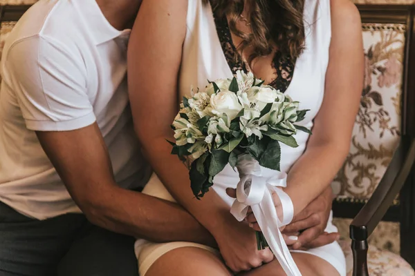 Sposa e sposo in un caffè. bouquet da sposa su un tavolo di legno in un ristorante gli sposi si tengono per mano . — Foto Stock