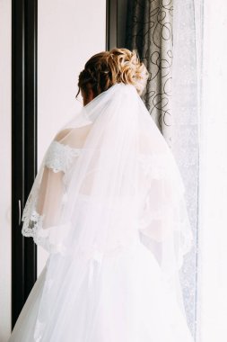 Gelinlikli gelin pencerenin yanında oturuyor, arka görüş