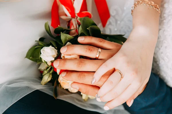 Mani con anelli sulle dita degli sposi sullo sfondo di un bouquet di nozze — Foto Stock