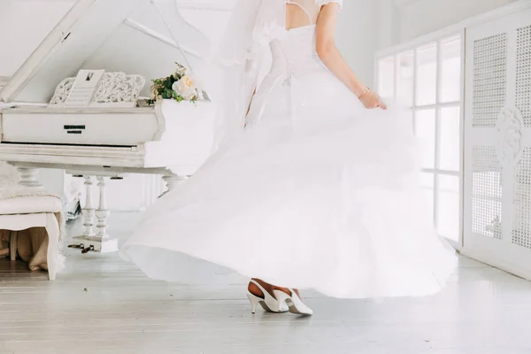 Mooie aantrekkelijke bruid in trouwjurk met lange volledige rok, witte achtergrond, dansen en lachen — Stockfoto
