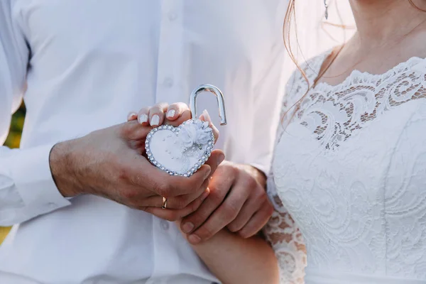 Serratura di nozze e chiave come simbolo di matrimonio nelle mani della sposa e dello sposo — Foto Stock