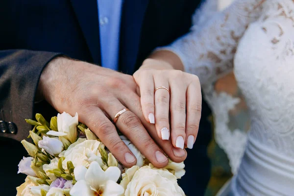 Primo piano. Mano della sposa e dello sposo. Sposa e sposo si tengono per mano. Concentrati sugli anelli. Bouquet in mano — Foto Stock