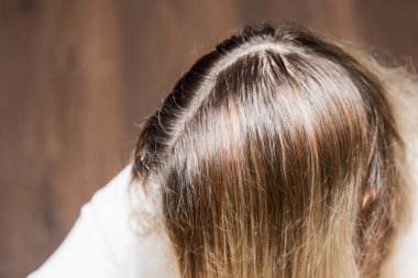 Gri olacak. Kadın beyaz saç köklerini gösteriyor. Kapat.