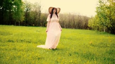 Art Village otantik güzellik retro bayanı, doğanın çiçek açan sarı alanının tadını çıkarın. Uyum kavramı. Uzun, beyaz, klasik bohem gelinlik treni. Hasır şapka kayıkçı çiçekler.