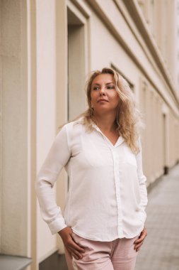 Klasik görünümlü güzel sarışın iş kadını sokakta yürüyor..