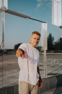 Şehirli yakışıklı bir adamın portresi. Modern cam ayna binasının arka planında genç bir adam.