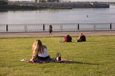 Parkta çimlerde oturan bir grup genç üniversite öğrencisi.