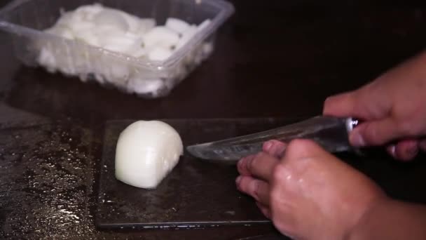 La mano sostiene un cuchillo. Cortando cebollas. El cocinero está en la cocina. — Vídeos de Stock