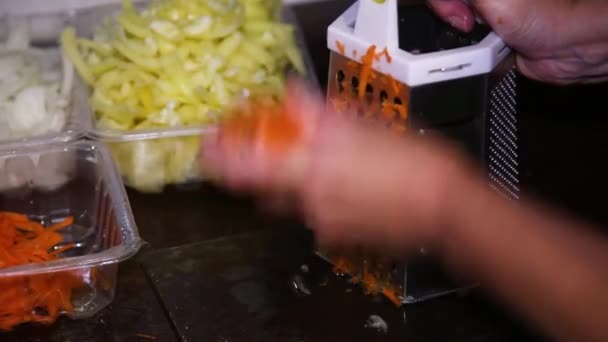 Ανθρώπινα χέρια σχάρα ακατέργαστο καρότο σε ένα τρίφτη μετάλλων — Αρχείο Βίντεο