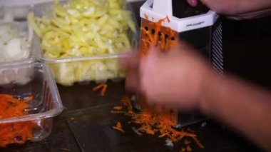 İnsan elleri metal rendeleyici üzerinde çiğ havuç rendeler.