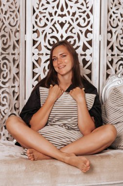 Pozitif kadın yatağında oturup yastığına sarılıyor.