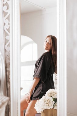 Küvetin kenarında oturan bornozlu genç ve güzel bir kadın. Kişisel bakım kavramı