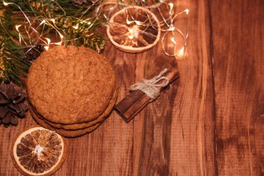Ahşap zemin üzerinde ev yapımı karamelli Noel kurabiyeleri, neon ışıklar, tarçın çubukları. Yeni Yıl