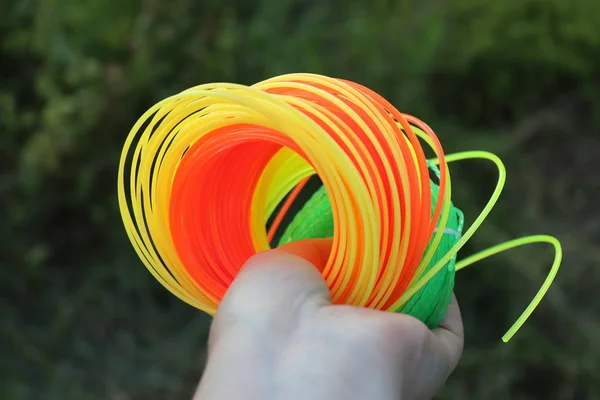 Neon strings for grass trimmer in woman\'s hand