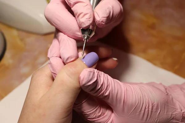 Taking off the manicure with milling cutter. Safe manicure concept. Medical gloves. Lavender manicure