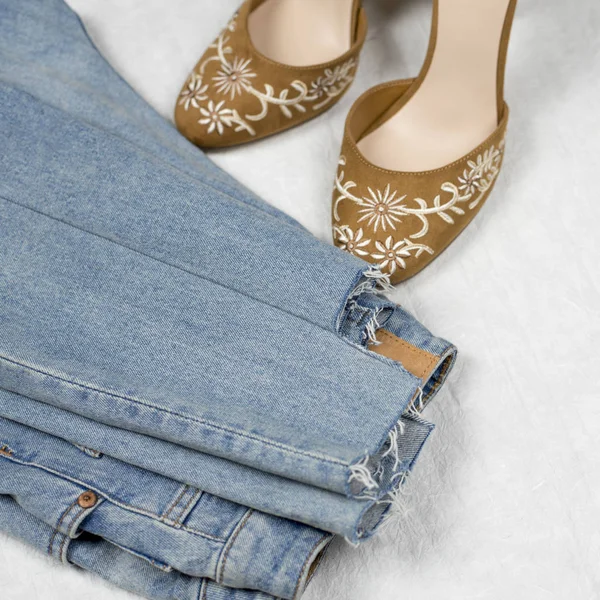 fBlue jeans and highheels shoes with embroidery flatlay on a white background