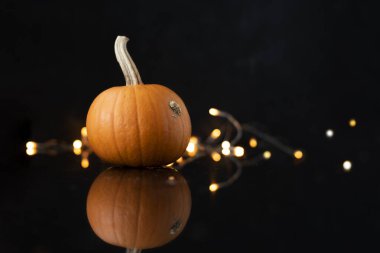 Yüzeyden yansıyan parlak turuncu pompalama ve siyah arkaplanda ışıklar