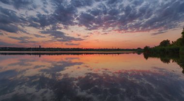 Ukraynalı yaz günbatımı manzara ile durgun su tarafından yansıyan bulutlu gökyüzü