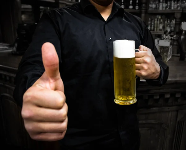 a barman giving a thumbs up holding a beer