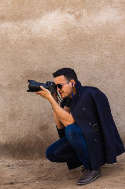 fotoğrafçı bir kamera karşısında gözünü onun elinde sabit duruyor siyah güneş gözlüğü ile karanlık kıyafeti giymiş. Bir atış yapma.
