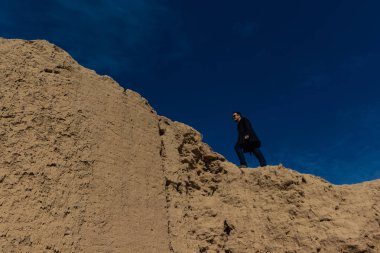 bir erkekte koyu bir kıyafet ve antik duvar üzerine tırmanma siyah güneş gözlüğü. Başarı ve ilerlemeye veya yukarı doğru kavramı.